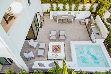 This is an example of a small contemporary drought-tolerant and full sun backyard concrete paver landscaping in Orange County with a fire pit.