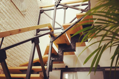На фото: изогнутая деревянная лестница среднего размера в стиле лофт с деревянными ступенями и металлическими перилами