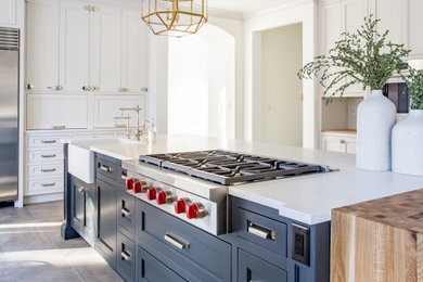Inspiration for a large timeless galley porcelain tile and gray floor eat-in kitchen remodel in Denver with a farmhouse sink, recessed-panel cabinets, white cabinets, quartzite countertops, white backsplash, quartz backsplash, stainless steel appliances, an island and white countertops