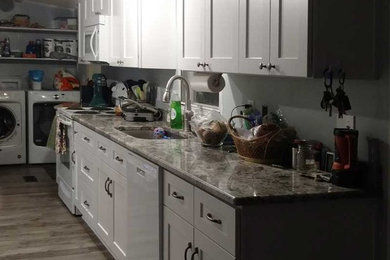 Foto de cocina actual de tamaño medio abierta con fregadero de un seno, armarios estilo shaker, puertas de armario blancas, encimera de granito, electrodomésticos de acero inoxidable y una isla