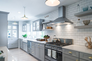 This is an example of a large country galley separate kitchen in Milwaukee with a farmhouse sink, shaker cabinets, grey cabinets, marble benchtops, white splashback, subway tile splashback, stainless steel appliances, porcelain floors, no island and beige floor.