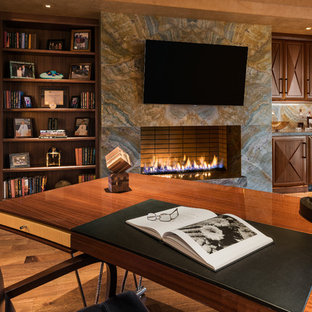 Photo of a large contemporary study room in Phoenix with brown walls, light hardwood floors, a ribbon fireplace, a stone fireplace surround and a freestanding desk.