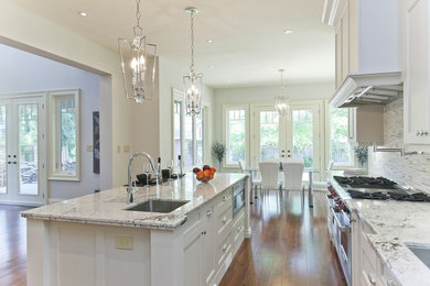 Eat-in kitchen - large transitional galley medium tone wood floor and brown floor eat-in kitchen idea in Toronto with an undermount sink, shaker cabinets, white cabinets, granite countertops, white backsplash, glass tile backsplash, stainless steel appliances and an island