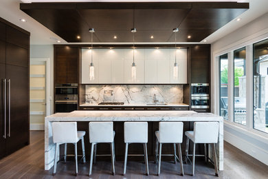 Example of a trendy l-shaped dark wood floor and brown floor kitchen design in Vancouver with a double-bowl sink, flat-panel cabinets, dark wood cabinets, gray backsplash, paneled appliances, an island and gray countertops