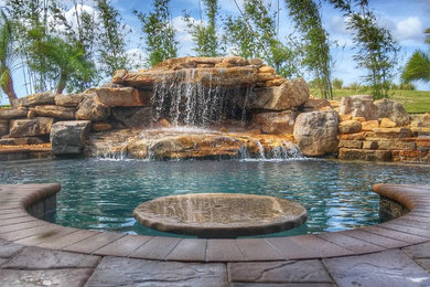 This is an example of a mid-sized transitional backyard custom-shaped pool in Orlando with a water feature and brick pavers.