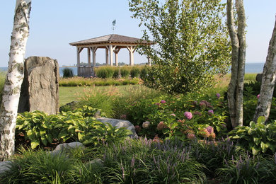 This is an example of a large traditional partial sun backyard landscaping in New York.