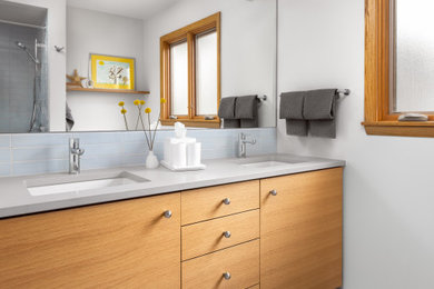 Mid-sized 1950s kids' blue tile and ceramic tile porcelain tile, gray floor and double-sink bathroom photo in Milwaukee with light wood cabinets, a two-piece toilet, gray walls, an undermount sink, quartz countertops, gray countertops and a built-in vanity