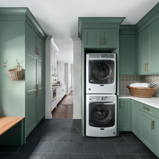 Inspiration for a medium sized classic u-shaped utility room in Chicago with a submerged sink, shaker cabinets, green cabinets, engineered stone countertops, white walls, porcelain flooring, a stacked washer and dryer, black floors and white worktops.