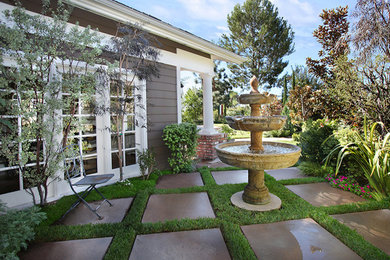 Photo of a small traditional full sun backyard concrete paver water fountain landscape in Orange County.