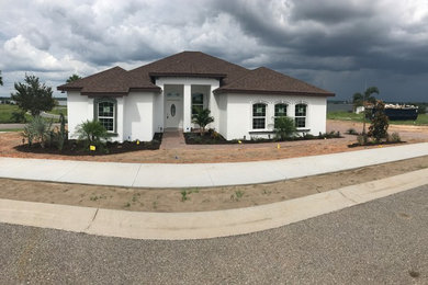 Large transitional white one-story concrete house exterior idea in Tampa with a shingle roof