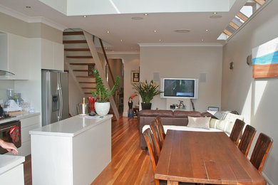 Photo of a small contemporary open plan dining in Sydney with multi-coloured walls, medium hardwood floors and brown floor.