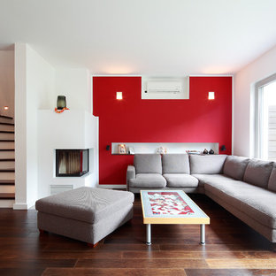 Idéer för ett mellanstort modernt allrum med öppen planlösning, med ett finrum, röda väggar, mörkt trägolv och en spiselkrans i gips