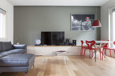 This is an example of a small contemporary open concept living room in Milan with grey walls, light hardwood floors and a wall-mounted tv.