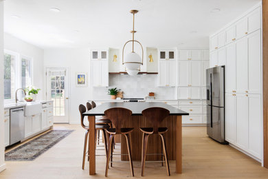 Inspiration for a large transitional u-shaped light wood floor and brown floor open concept kitchen remodel in Austin with an undermount sink, shaker cabinets, white cabinets, granite countertops, white backsplash, ceramic backsplash, stainless steel appliances, an island and black countertops
