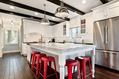 Mid-sized transitional l-shaped medium tone wood floor open concept kitchen photo in Chicago with a farmhouse sink, beaded inset cabinets, white cabinets, granite countertops, white backsplash, subway tile backsplash, stainless steel appliances and an island