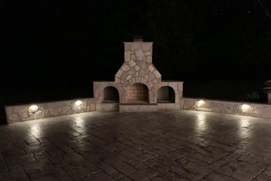 Inspiration for a large backyard stamped concrete patio remodel in Other with a fireplace