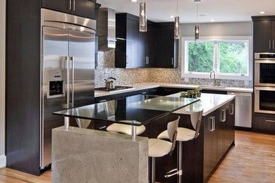 This is an example of a large contemporary l-shaped kitchen in Orange County with an undermount sink, flat-panel cabinets, black cabinets, solid surface benchtops, multi-coloured splashback, mosaic tile splashback, stainless steel appliances, medium hardwood floors, with island and brown floor.