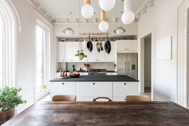 Foto de cocina nórdica abierta con armarios con paneles lisos, una isla y encimeras negras