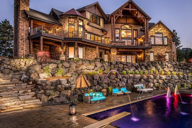 Huge mountain style backyard concrete paver and rectangular lap pool fountain photo in Seattle