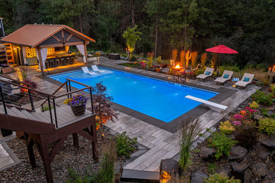 Diseño de casa de la piscina y piscina alargada de estilo americano extra grande rectangular en patio trasero con adoquines de piedra natural
