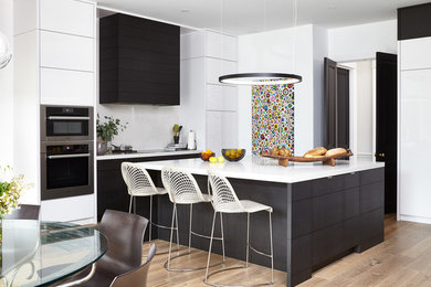 Mid-sized minimalist l-shaped light wood floor and beige floor eat-in kitchen photo in Toronto with flat-panel cabinets, white backsplash, stainless steel appliances, an island, quartz countertops and white countertops