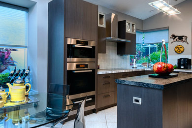 Photo of a contemporary eat-in kitchen in Miami with flat-panel cabinets, grey cabinets and stainless steel appliances.