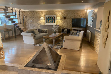 Cette image montre une grande salle de séjour design ouverte avec un mur gris, parquet clair, un manteau de cheminée en métal et un téléviseur d'angle.