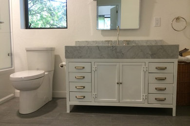 Large trendy master beige tile and stone tile slate floor bathroom photo in San Francisco with flat-panel cabinets, black cabinets, a one-piece toilet, white walls, an undermount sink and marble countertops