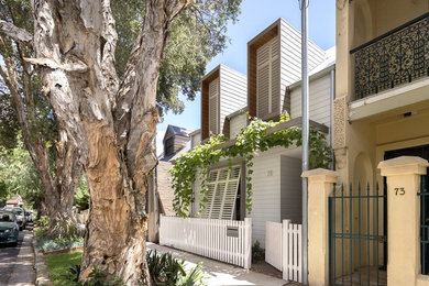 Photo of a small contemporary two-storey white exterior in Sydney with wood siding.