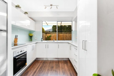 Photo of a modern kitchen in Sunshine Coast with white cabinets and blue splashback.