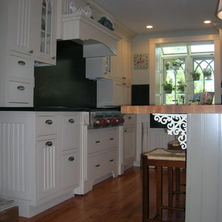 Mid-sized farmhouse kitchen pantry designs - Example of a mid-sized farmhouse l-shaped kitchen pantry design in Manchester with an island