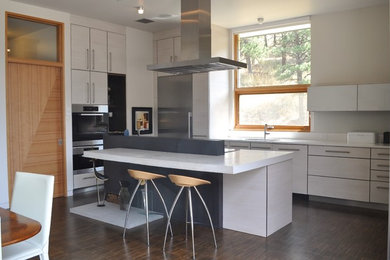 Inspiration for a mid-sized contemporary l-shaped eat-in kitchen in Denver with an undermount sink, flat-panel cabinets, beige cabinets, concrete benchtops, white splashback, stainless steel appliances, dark hardwood floors, with island and brown floor.