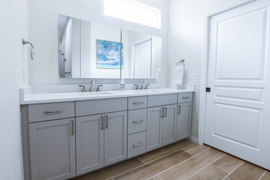 Inspiration for a mid-sized modern master gray tile and ceramic tile brown floor, double-sink and porcelain tile bathroom remodel in Tampa with shaker cabinets, gray cabinets, an undermount sink, a hinged shower door, white countertops, a built-in vanity, a two-piece toilet, white walls and quartz countertops
