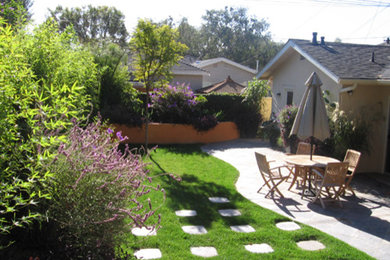 Ejemplo de jardín contemporáneo de tamaño medio en patio trasero con muro de contención y adoquines de piedra natural