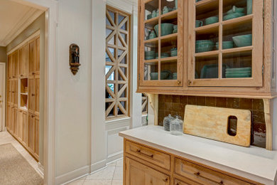 Inspiration for a mid-sized timeless galley travertine floor, beige floor and exposed beam enclosed kitchen remodel in Houston with a farmhouse sink, beaded inset cabinets, medium tone wood cabinets, quartz countertops, brown backsplash, ceramic backsplash, paneled appliances, a peninsula and beige countertops