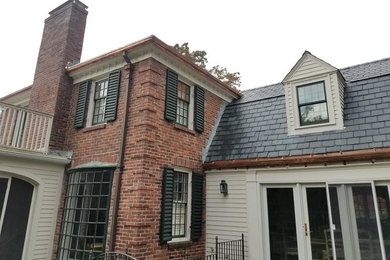 Large traditional two-storey white house exterior in Boston with mixed siding, a gambrel roof and a tile roof.