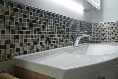 Kleines Modernes Duschbad mit flächenbündigen Schrankfronten, weißen Schränken, bodengleicher Dusche, Wandtoilette, beigen Fliesen, Keramikfliesen, beiger Wandfarbe, Keramikboden, Einbauwaschbecken, Mineralwerkstoff-Waschtisch, beigem Boden, Falttür-Duschabtrennung und weißer Waschtischplatte in Berlin