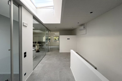 Immagine di un grande ingresso o corridoio moderno con pareti bianche, pavimento in gres porcellanato, pavimento grigio e soffitto ribassato