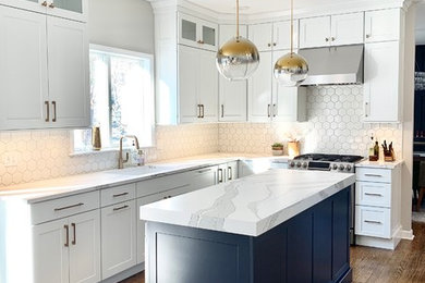 Example of a transitional l-shaped kitchen design with shaker cabinets, white cabinets, quartz countertops, white backsplash, an island and white countertops