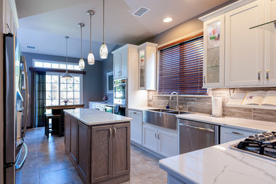 Enclosed kitchen - mid-sized transitional l-shaped porcelain tile and multicolored floor enclosed kitchen idea in Philadelphia with a farmhouse sink, shaker cabinets, white cabinets, quartzite countertops, brown backsplash, stone tile backsplash, stainless steel appliances, an island and white countertops