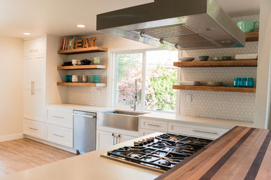 Mid-sized minimalist u-shaped light wood floor kitchen photo in Santa Barbara with a farmhouse sink, recessed-panel cabinets, white cabinets, quartz countertops, white backsplash, mosaic tile backsplash, stainless steel appliances and an island