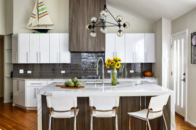 Inspiration for a large contemporary medium tone wood floor, brown floor and vaulted ceiling eat-in kitchen remodel in DC Metro with an undermount sink, flat-panel cabinets, white cabinets, quartz countertops, brown backsplash, glass tile backsplash, stainless steel appliances, an island and white countertops
