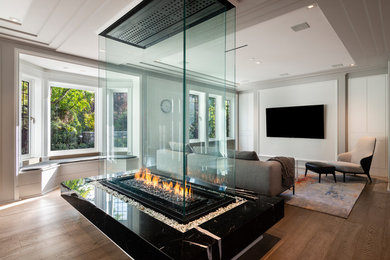 Example of a large trendy formal and open concept brown floor and painted wood floor living room design in Vancouver with white walls, a two-sided fireplace, a stone fireplace and a wall-mounted tv