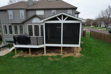 Inspiration for a large timeless screened-in and metal railing back porch remodel in Kansas City with a roof extension