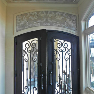 Bild på en stor eklektisk ingång och ytterdörr, med gula väggar, kalkstensgolv, en dubbeldörr och en svart dörr