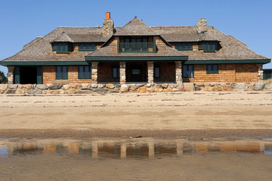 Photo of a beach style two-storey house exterior in New York with wood siding and a hip roof.