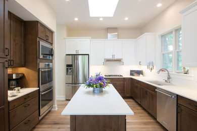 グランドラピッズにあるトランジショナルスタイルのおしゃれなキッチン (アンダーカウンターシンク、白いキッチンパネル、シルバーの調理設備、ベージュの床、白いキッチンカウンター) の写真