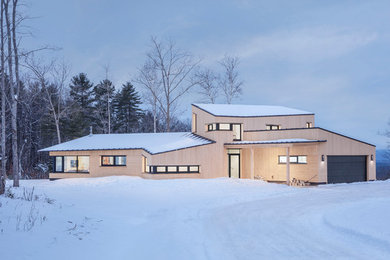 Example of a small trendy brown two-story wood house exterior design in Portland Maine with a shed roof and a metal roof