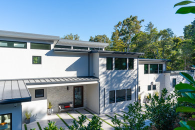 Inspiration for a large contemporary white three-story stucco house exterior remodel in San Francisco with a shed roof, a metal roof and a gray roof