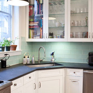 Inspiration pour une arrière-cuisine design en U de taille moyenne avec un évier encastré, un placard à porte vitrée, des portes de placard blanches, une crédence bleue, une crédence en carreau de verre et un électroménager en acier inoxydable.